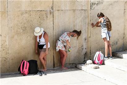 Touristinnen kühlen sich am Trevi-Brunnen in Italien im Schatten ab
