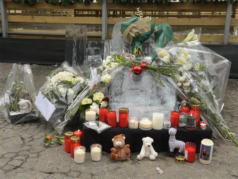 Trauernde legen Blumen, Kerzen und Kuscheltiere am Knuedler-Unglücksort mit Eisschlitten-Skulptur ab