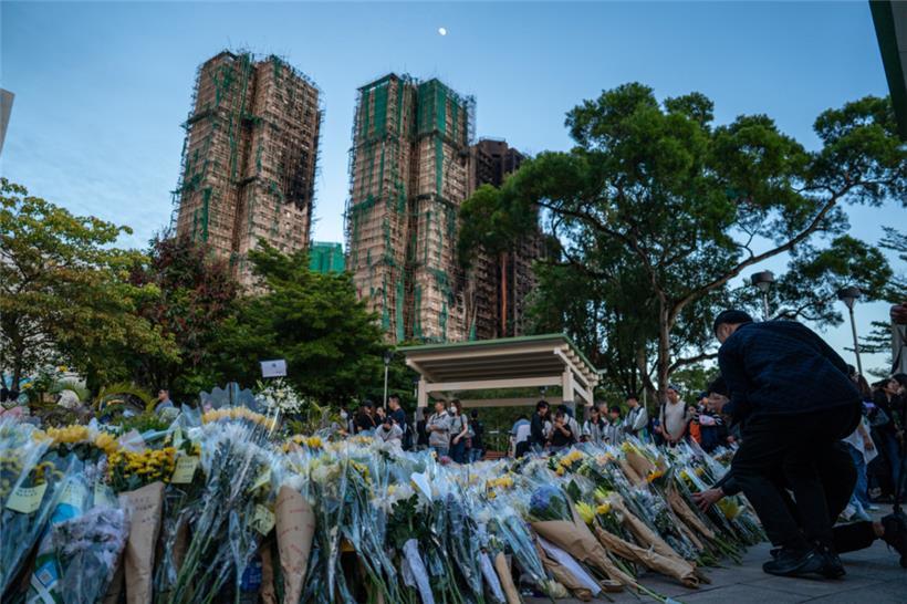 Trauernde legen nach dem tödlichen Brand Blumen an einer behelfsmäßigen Gedenkstätte in der Nähe des Wohnkomplexes Wang Fuk Court in Tai Po nieder.

