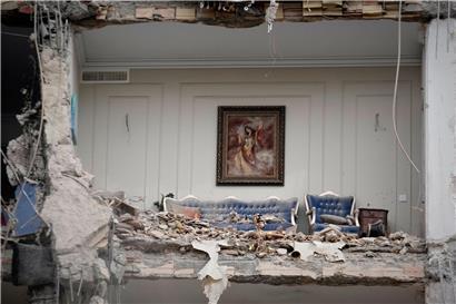 Zerstörtes Wohnzimmer in Teheran mit Trümmern auf Möbeln nach Gebäudeschaden