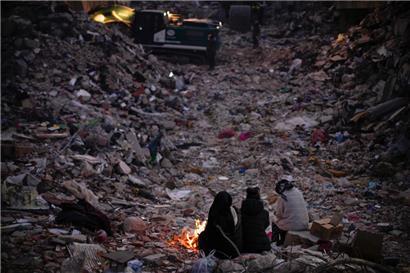 Türkei, Antakya: Mitglieder einer Familie halten sich neben einem Feuer warm
