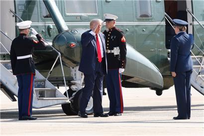 US-Präsident Donald Trump (M) wird von der stellvertretenden Kommandeurin des 89. Luftwaffengeschwaders der Air Force, Melissa Dombrock (r) begrüßt, als er von der Marine One kommt, bevor er an Bord der Air Force One geht. 
