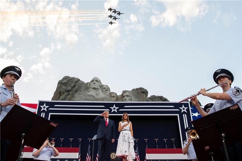 US-Präsident Donald Trump und First Lady Melania Trump stehen während der Nationalhymne am Denkmal Mount Rushmore, während über ihnen Kampfflugzeuge der US Navy fliegen. 

