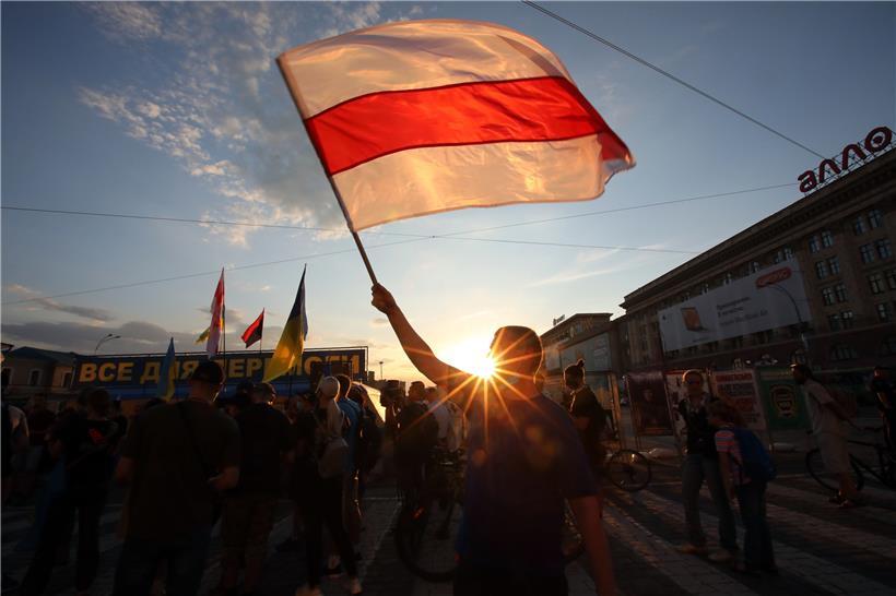 Ukraine, Charkiw: Ein Aktivist schwenkt auf dem Freiheitsplatz eine historische Flagge von Belarus bei einer Kundgebung zum Stopp der Diktatur in Belarus in Solidarität mit den belarussischen Bürgerinnen und Bürgern. Der belarussische Staatschef Lukaschenko soll die Präsidentenwahl mit rund 80 Prozent der Stimmen klar gewonnen haben, ihm werden allerdings massive Wahlfälschungen vorgeworfen.
