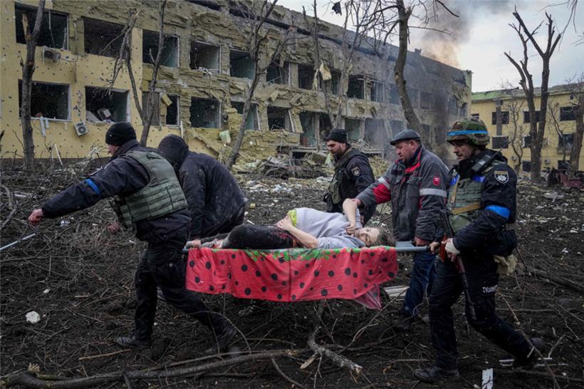 Ukrainische Rettungskräfte und Freiwillige tragen eine verletzte schwangere Frau aus einer Entbindungsklinik, die durch russischen Beschuss in Mariupol zerstört wurde
