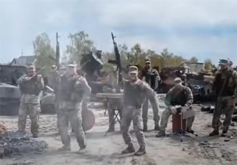 Ukrainische Soldaten spielen den Bayraktar-Song vor zerschossenen russischen Panzern
