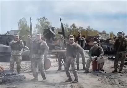 Ukrainische Soldaten spielen den Bayraktar-Song vor zerschossenen russischen Panzern
