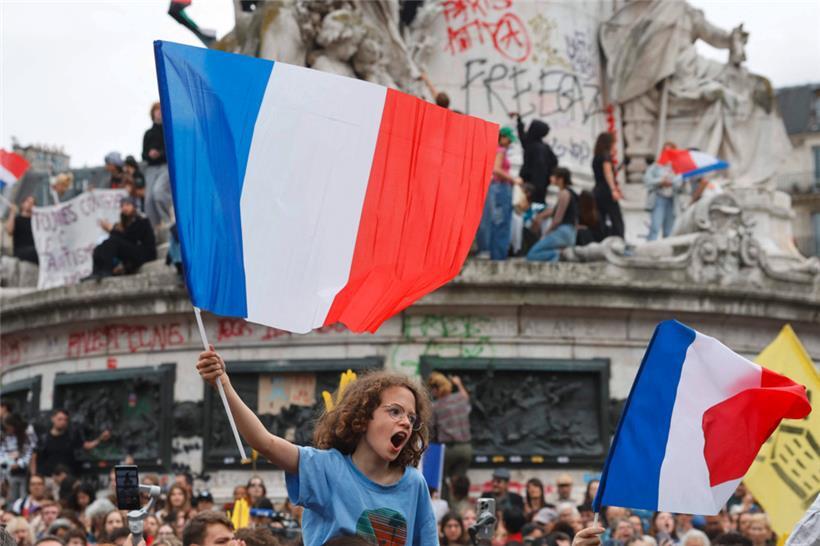 Un garçon brandit un drapeau français alors que des manifestants participent à un rassemblement contre l’extrême droite, place de la République à Paris
