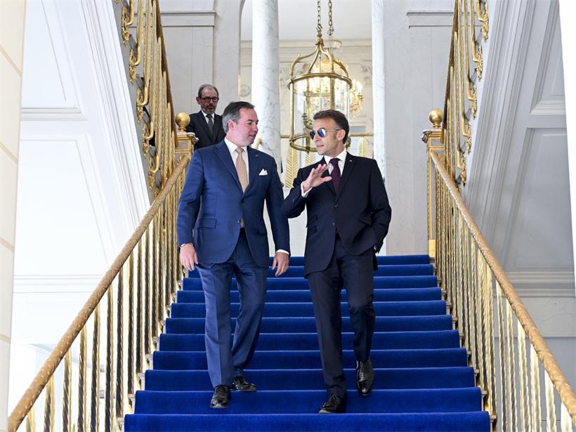 Emmanuel Macron erklärt Guillaume international Diplomatie, symbolisch mit Trump im Hintergrund, politische Führung und Dialog