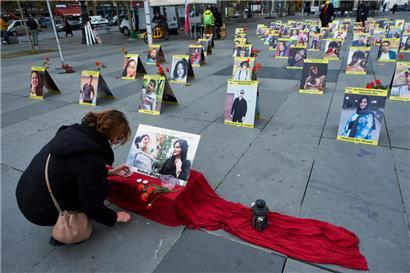 Une femme décore l’une des photos d’hommes et de femmes tués lors des récentes manifestations en Iran contre le régime islamiste, le 2 décembre à Paris. 
