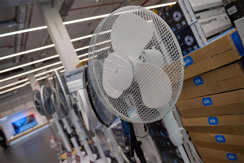 „Zwei Monate Wartezeit“ – Warum es für Klimaanlagen bereits zu spät ist Ventilator auf Schreibtisch als temporäre Kühlungslösung bei Sommerhitze im Büro