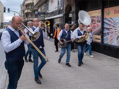 Passanten filmen und begleiten Straßenmusiker bei Auftritten in belebtem Stadtviertel