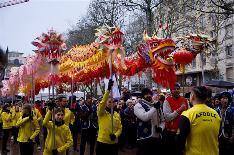 Vier leuchtend bunte Drachen tanzen durch die Straßen der Stadt