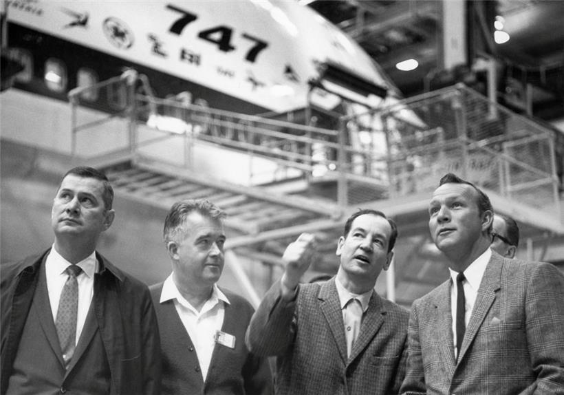 V.l.n.r.: Tex Bouillion, Vizepräsident und Generaldirektor der Boeing-Abteilung für kommerzielle Flugzeuge, George Nible, Direktor der Abteilung in Everett, Joe Sutter, Luftfahrtingenieur und Chefentwickler für das damals neue Großraumflugzeug Boeing 747, und Profi-Golfer Arnold Palmer, der das Flugzeug testfliegen durfte, stehen in einer Halle vor einer 747. 
