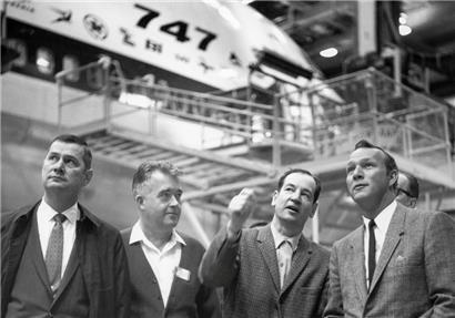 V.l.n.r.: Tex Bouillion, Vizepräsident und Generaldirektor der Boeing-Abteilung für kommerzielle Flugzeuge, George Nible, Direktor der Abteilung in Everett, Joe Sutter, Luftfahrtingenieur und Chefentwickler für das damals neue Großraumflugzeug Boeing 747, und Profi-Golfer Arnold Palmer, der das Flugzeug testfliegen durfte, stehen in einer Halle vor einer 747. 
