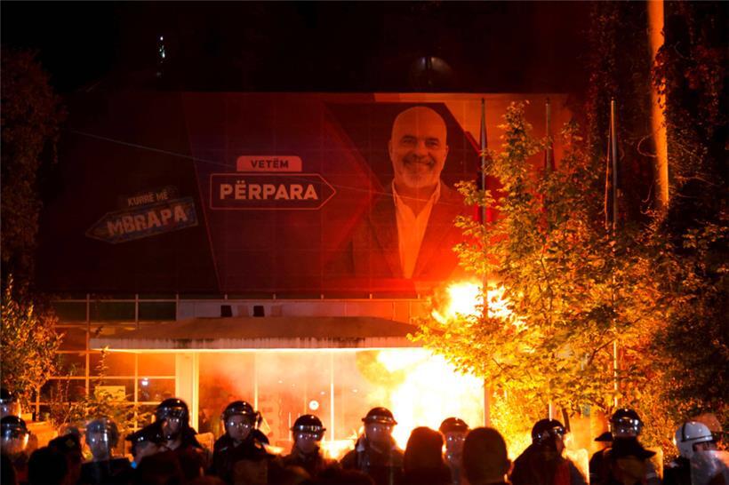 Von einem Werbeplakat lächelt Premierminister Edi Rama herab, während unten die Bereitschaftspolizei den Demonstranten der Opposition gegenüber steht
