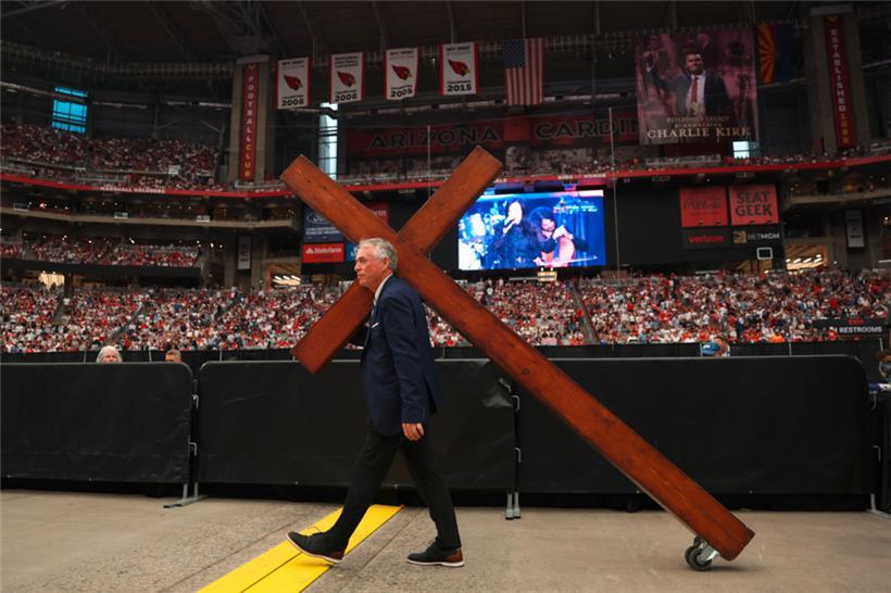 Vor der öffentlichen Gedenkfeier wird ein großes Kreuz hereingerollt
