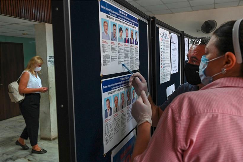 Wähler informieren sich in einem Wahllokal über antretende Kandidaten
