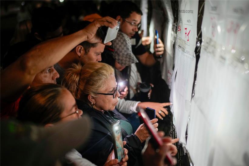 Wähler sehen sich die Wählerlisten vor der Öffnung der Wahllokale für die Präsidentschaftswahlen an. Die Wähler gehen heute an die Urnen, um zu entscheiden, ob Präsident Maduro für eine dritte Amtszeit wiedergewählt werden soll.
