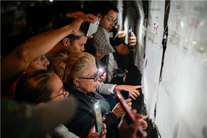 Wähler sehen sich die Wählerlisten vor der Öffnung der Wahllokale für die Präsidentschaftswahlen an. Die Wähler gehen heute an die Urnen, um zu entscheiden, ob Präsident Maduro für eine dritte Amtszeit wiedergewählt werden soll.
