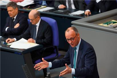 Während sich der CDU-Kanzlerkandidat Friedrich Merz am Rednerpult abmüht, wälzt Kanzler Olaf Scholz sich durch Dokumente
