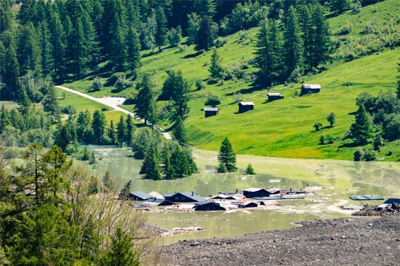 Wasser aus dem Fluss Lonza fließt über Schlamm und Stein, nachdem sich ein See um den letzten Häusern des Dorfes Blatten gebildet hat
