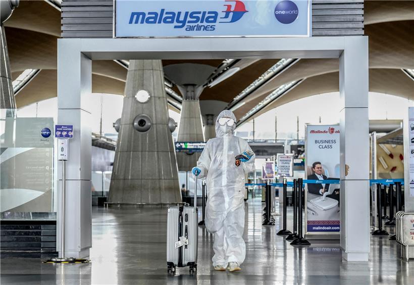 Weltweite Sorge: In Malaysia geht der Passagier Duan Rebecca vor dem Abflug nach Guangzhou mit Schutzkleidung und Trolley durch die Abflughalle des internationalen Flughafens von Kuala Lumpur.
