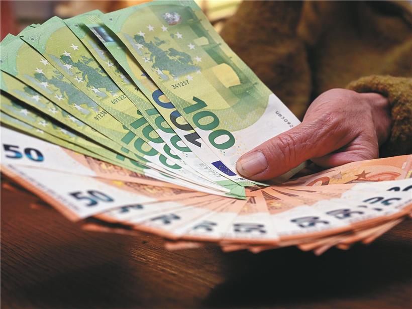 Mann gibt Geldscheine mit beiden Händen aus, Symbol für finanziellen Verlust und unkontrolliertes Ausgeben