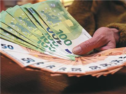 Mann gibt Geldscheine mit beiden Händen aus, Symbol für finanziellen Verlust und unkontrolliertes Ausgeben
