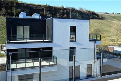 Modernes Wohnhaus mit Terrasse in grüner Umgebung nahe Weinberg und Naturkulisse