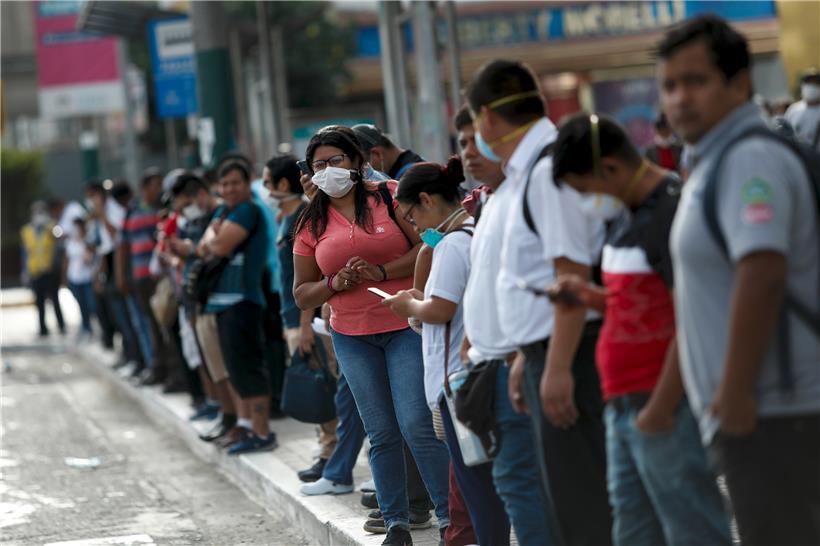 Zahlreiche Menschen mit Mundschutz stehen in Lima (Peru) am Straßenrand. Die Regierung von Peru hat Beschränkungen eingeführt, um die Ausbreitung des neuen Coronavirus einzuschränken
