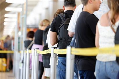 Zahlreiche Passagiere stehen innerhalb und außerhalb eines Terminals an, um durch die Sicherheitskontrolle zu gelangen
