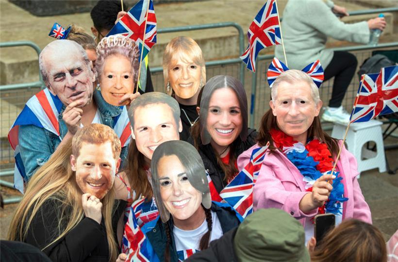 Zuschauer mit königlichen Masken stehen vor der Krönungszeremonie von König Charles III. und Königin Camilla im Zentrum Londons
