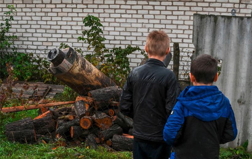 Zwei Jungen betrachten die Überreste einer Rakete, die in der Nähe einer Gebäudewand in Kramatorsk, Region Donezk, am 4. Oktober 2022 inmitten der russischen Invasion in der Ukraine eingeschlagen ist

