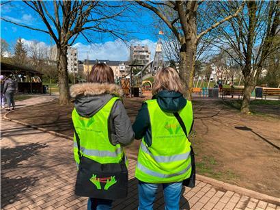 Zwei Mitarbeiterinnen der „Eltereschoul“ stehen auf einem Spielplatz und versuchen, mit Eltern ins Gespräch zu kommen
