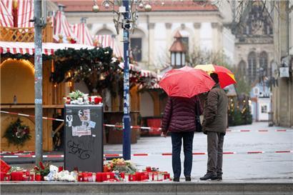 Zwei Passanten mit Regenschirmen stehen vor dem Weihnachtsmarkt
