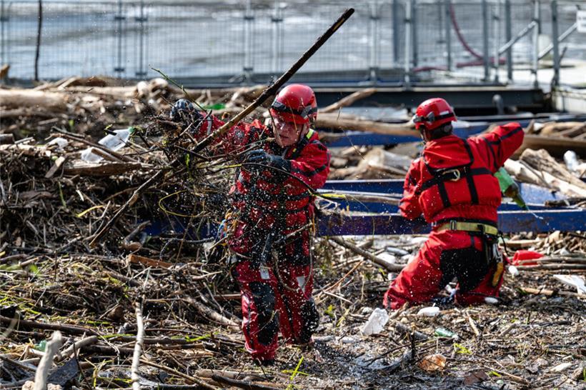 Zwei Personen entfernen nach dem Hochwasser Schlamm und Äste von der Anlegestelle vor der Wonka-Brücke
