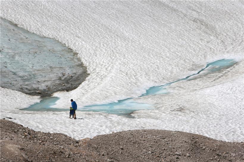 Zwei Wanderer gehen über den Schneeferner-Gletscher auf der Zugspitze
