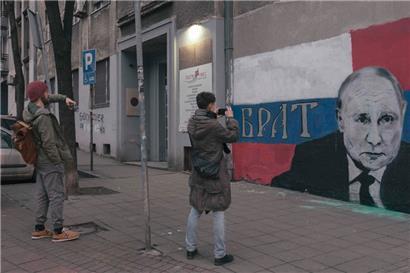 Zwei nach Belgrad geflüchtete Russen fotografieren ein Putin-Wandbild in der serbischen Hauptstadt
