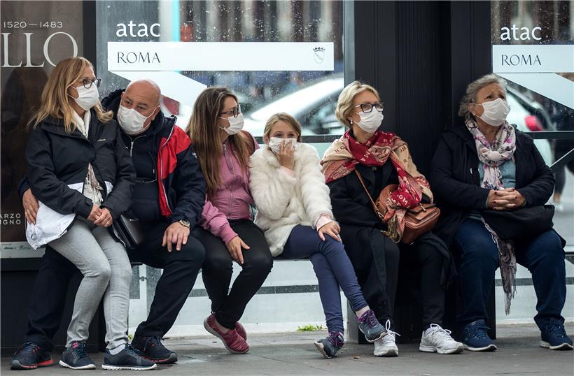 talien, Rom: Reisende mit Mundschutzmasken warten an einer Bushaltestelle. Italien hat die höchste Zahl an nachgewiesenen Covid-19-Toten nach China.
