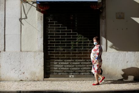 Eine Frau mit einer Gesichtsmaske geht an einem geschlossenen Restaurant in Lissabons Innenstadt vorbei