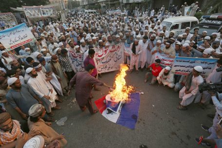 Anhänger einer religiösen Gruppe verbrennen während eines Protestes gegen die Veröffentlichung von Karikaturen des Propheten Mohammed Darstellungen der französischen Flagge und des französischen Präsidenten Macron