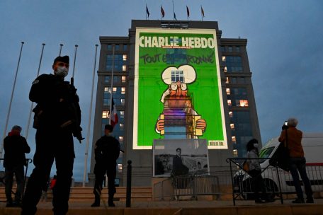 21.10.2020, Frankreich, Montpellier: Polizeibeamte stehen Wache, während bei einer landesweiten Gedenkveranstaltung an den ermordeten Lehrer Samuel Paty Karikaturen der französischen Satirezeitung Charlie Hebdo auf die Fassade des Hotel de Region in Montpellier projiziert werden. 