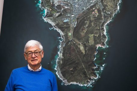 „Insel“ Esch: Schöffe Martin Kox in seinem Büro vor einem Bild von Serge Ecker, das die Gemeinde aus der Vogelperspektive als Insel im Meer darstellt