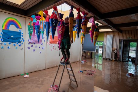 Eine Frau hängt im Kindergarten Kordel die an der Decke hängenden Schultüten ab
