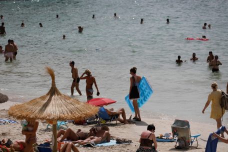 Einheimische und Touristen kühlen sich im Meer am Strand Cala Major in Palma de Mallorca ab