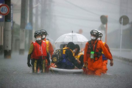 Japan, Kurume: Feuerwehrleute tragen gestrandete Anwohner auf einem Boot durch eine von starkem Regen überflutete Straße in Kurume, Präfektur Fukuoka, Westjapan. Sintflutartige Regenfälle, die den Südwesten Japans heimsuchten, lösten am frühen Freitag eine Schlammlawine aus, die einige Menschen verschluckte und zu Überschwemmungen und weiteren Erdrutschen in der Region zu führen drohte. 