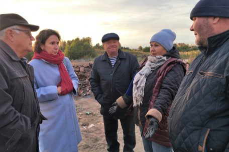 Jelena Wachtina (im blauen Mantel) lässt sich von den Dorfbewohnern von Sadowy berichten, wie auf der illegalen Mülldeponie hinter ihren Häusern Abfall verbrannt wird