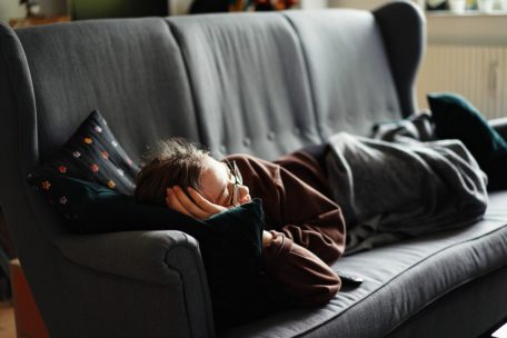 Schlapp und müde nachmittags auf der Couch liegen sind typische Anzeichen einer chronischen Schlafaufschieberitis