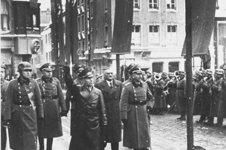 Luxemburg unter dem Hakenkreuz. Gauleiter Gustav Simon (1. Reihe, M.) inspiziert eine Truppe. Der in zivil gekleidete Mann (2. Reihe) ist der Hauptkollaborateur Luxemburgs, Professor Damian Kratzenberg, Landesleiter der Volksdeutschen Bewegung. Nach dem Krieg wurde Kratzenberg zum Tode verurteilt und hingerichtet. Fotograf unbekannt.